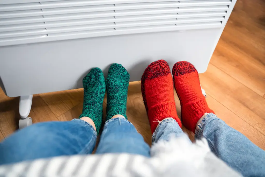 dos personas con los pies cerca de la calefacción
